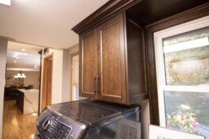 Close-up of custom dark wooden upper cabinetry in laundry room.