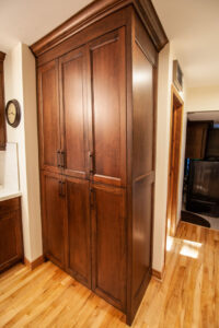 Custom dark wooden built-in pantry in kitchen.