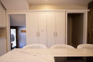 2 large white custom double door built-in pantries in a kitchen.