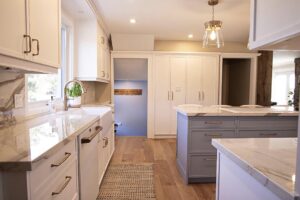 Large custom white kitchen with blue grey island and marble counter tops.